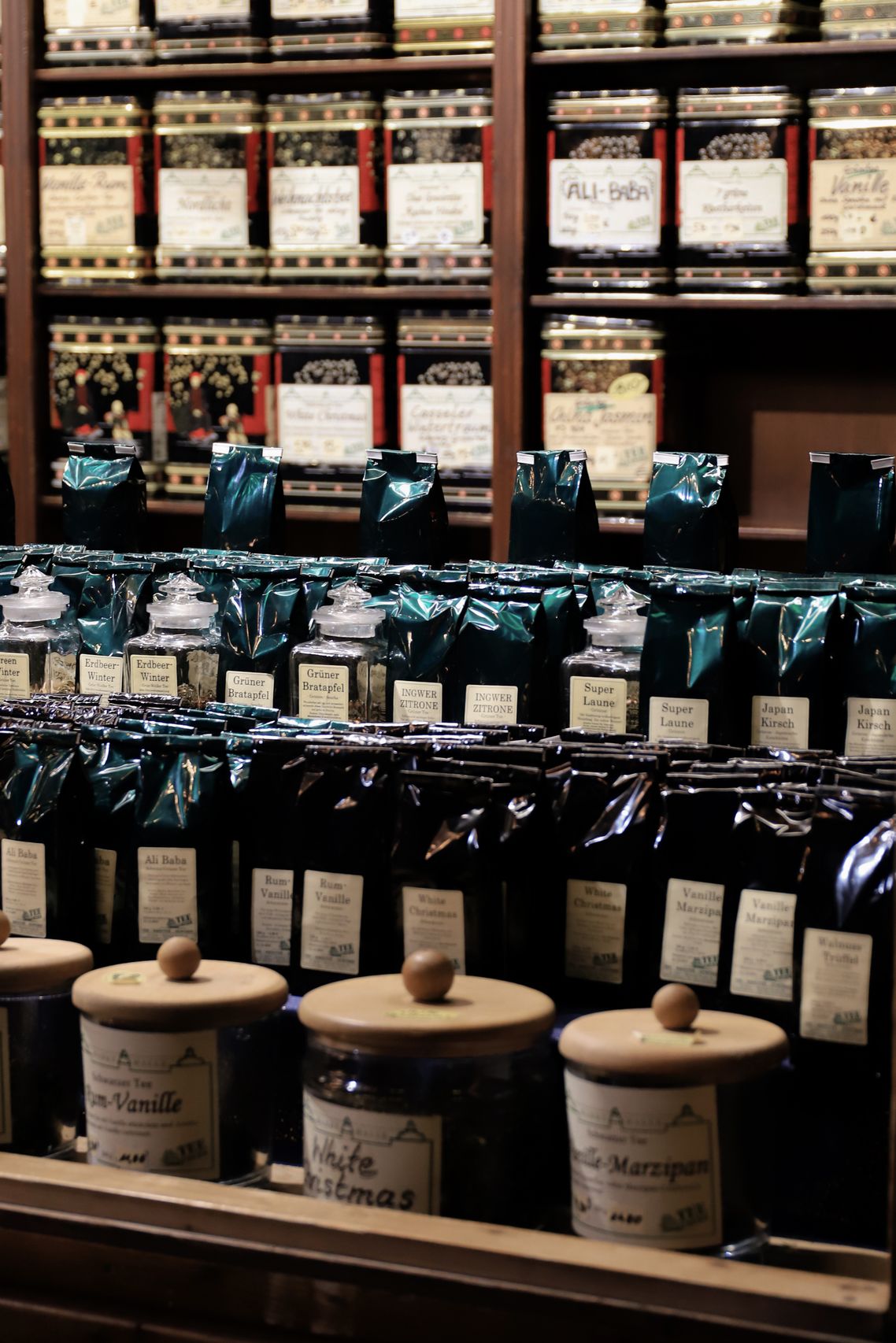 Sarah and Daniel wearing aprons standing inside the tea shop with shelves of tea jars